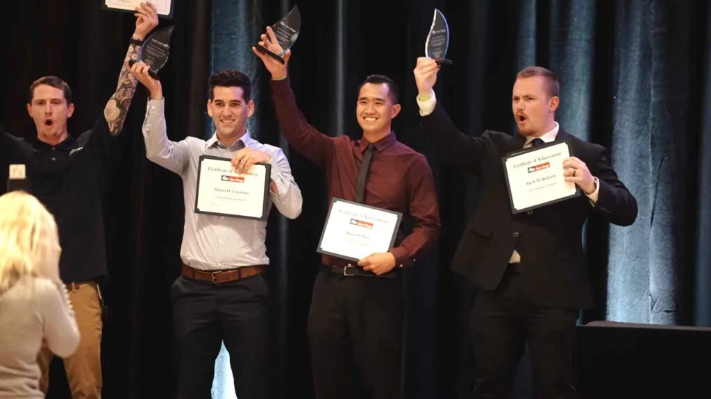 Young men on stage holding certificates and awards