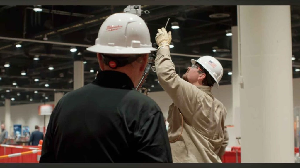 Two workers in hard hats inspecting equipment at an event