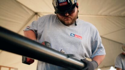 Construction worker in hard hat using a power tool at a competition