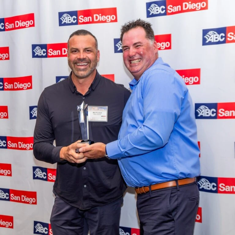 Two men posing with an award at a step-and-repeat banner