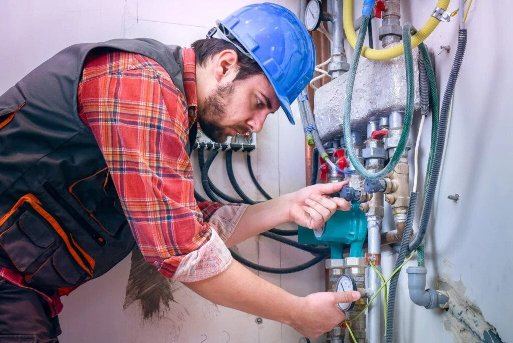 Worker in hard hat adjusting valves and piping