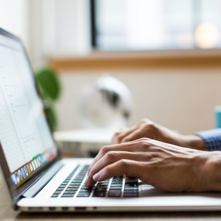 Close-up of hands typing on a laptop keyboard