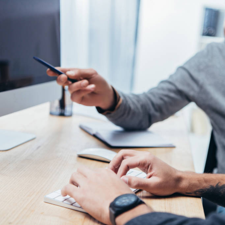 Two people working at a desk with keyboard and phone