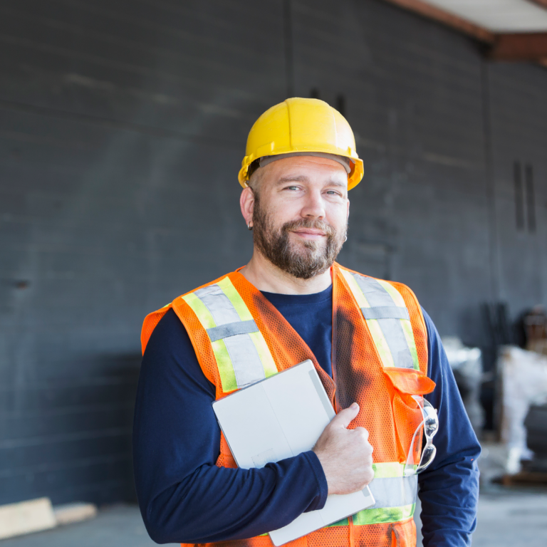 Worker in hard hat and safety vest holding a laptop