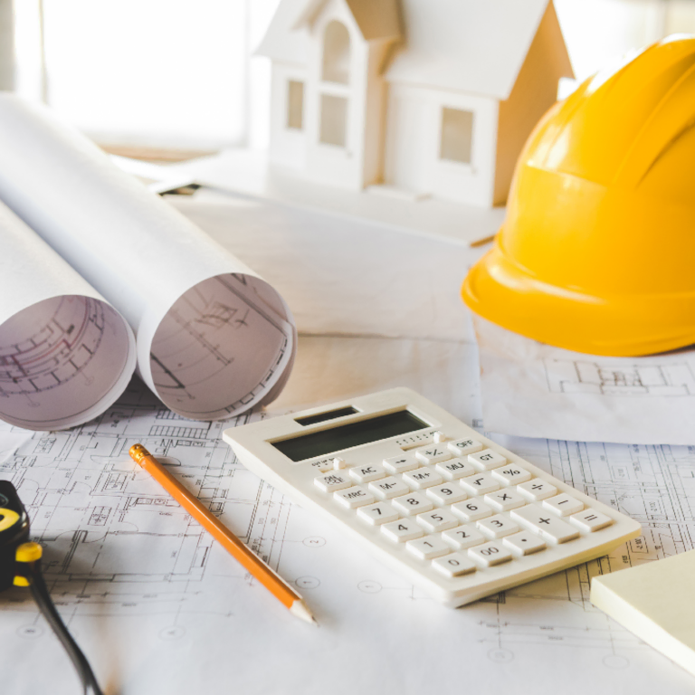 Calculator, blueprints and hard hat on a desk