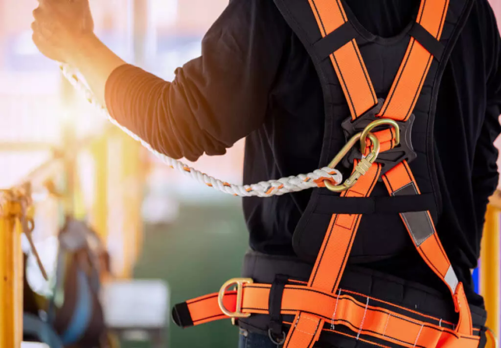 Close-up of a worker wearing an orange fall-protection safety harness