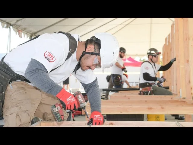 Worker using a drill on lumber at a construction competition
