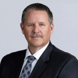 Professional headshot of a man with a mustache in a suit