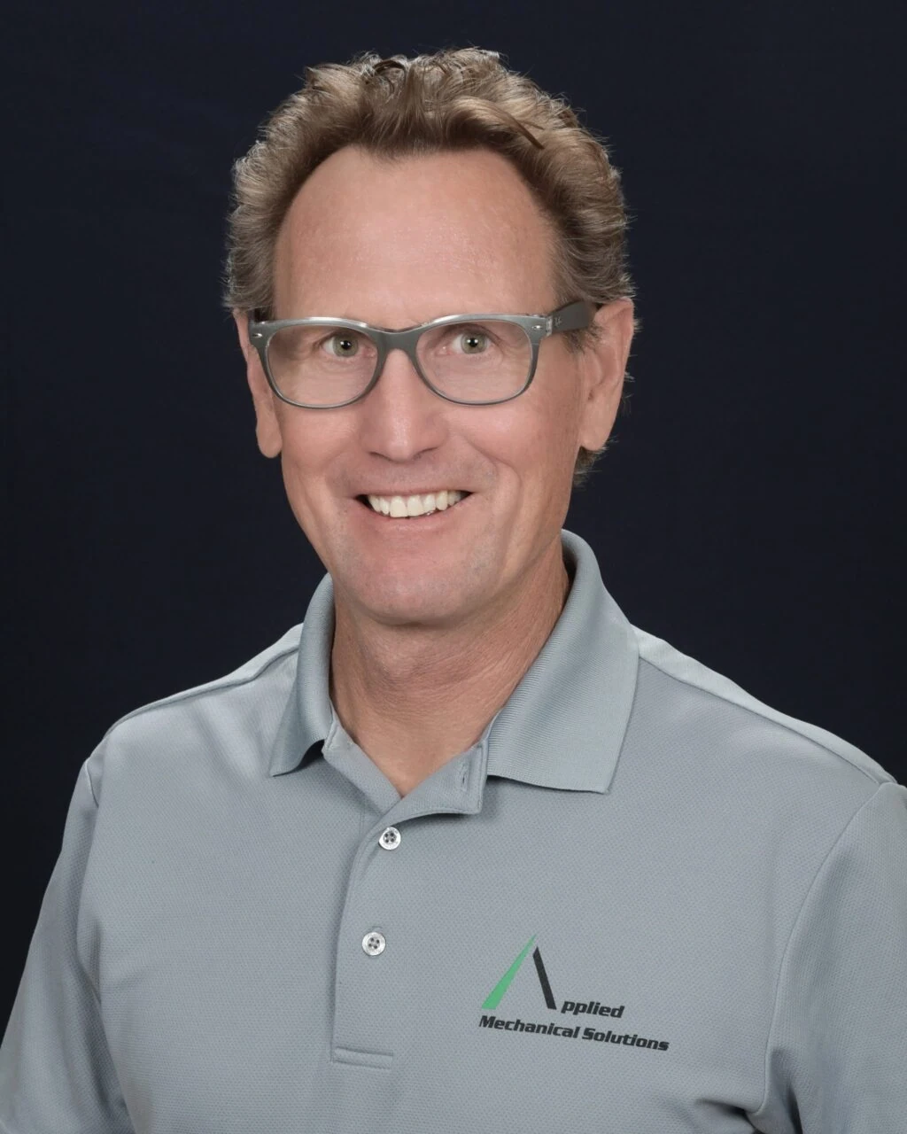 Professional headshot of a man in glasses and a gray polo shirt