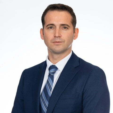 Professional headshot of a man in a navy suit and tie