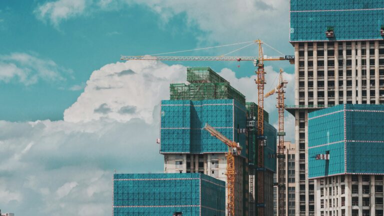 High-rise building under construction with cranes and scaffolding.
