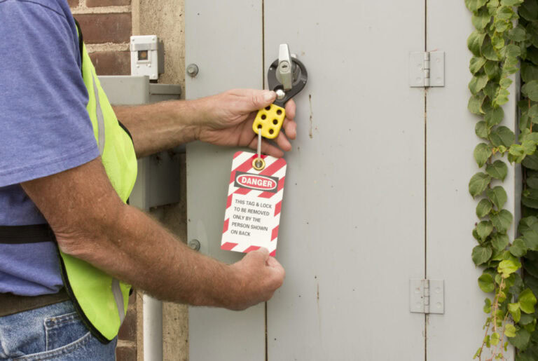 Worker attaching a lockout tagout danger tag to an electrical panel