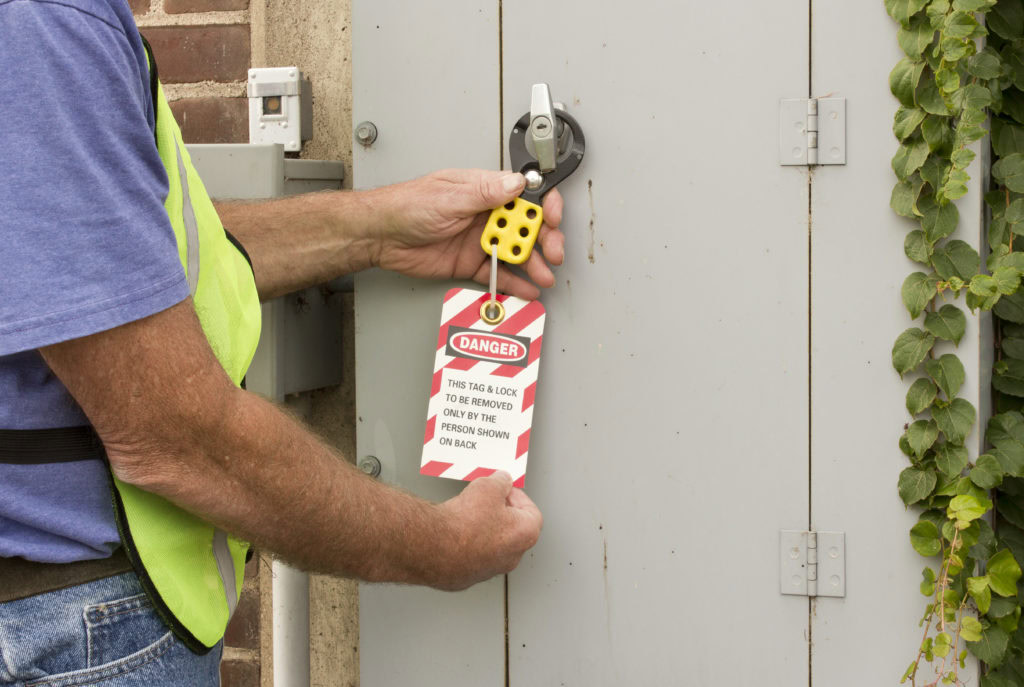 Worker attaching a lockout tagout danger tag to an electrical panel