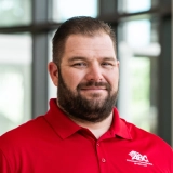 Professional headshot of a bearded man in a red polo shirt