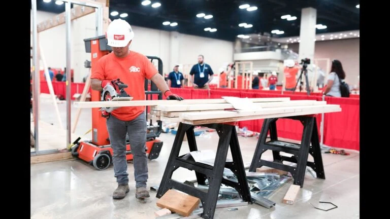 Worker cutting lumber with a circular saw at an indoor competition