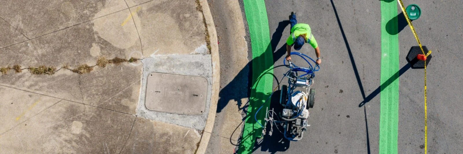 Aerial view of a worker painting a green line on pavement