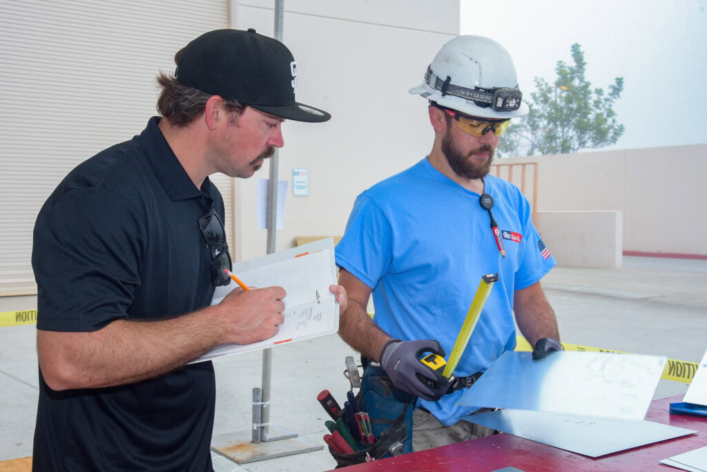 Two construction workers reviewing plans outdoors at a construction site.