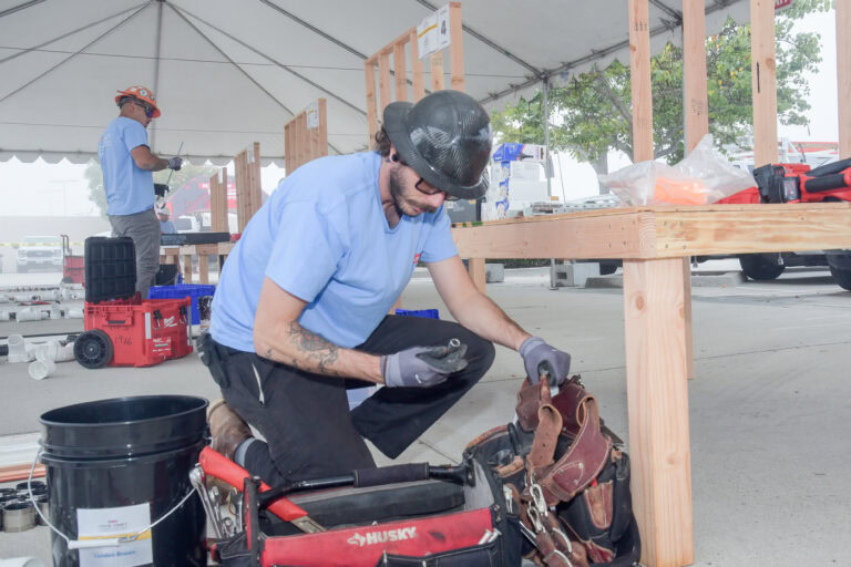 Construction worker in safety gear working on a wooden structure at the event.